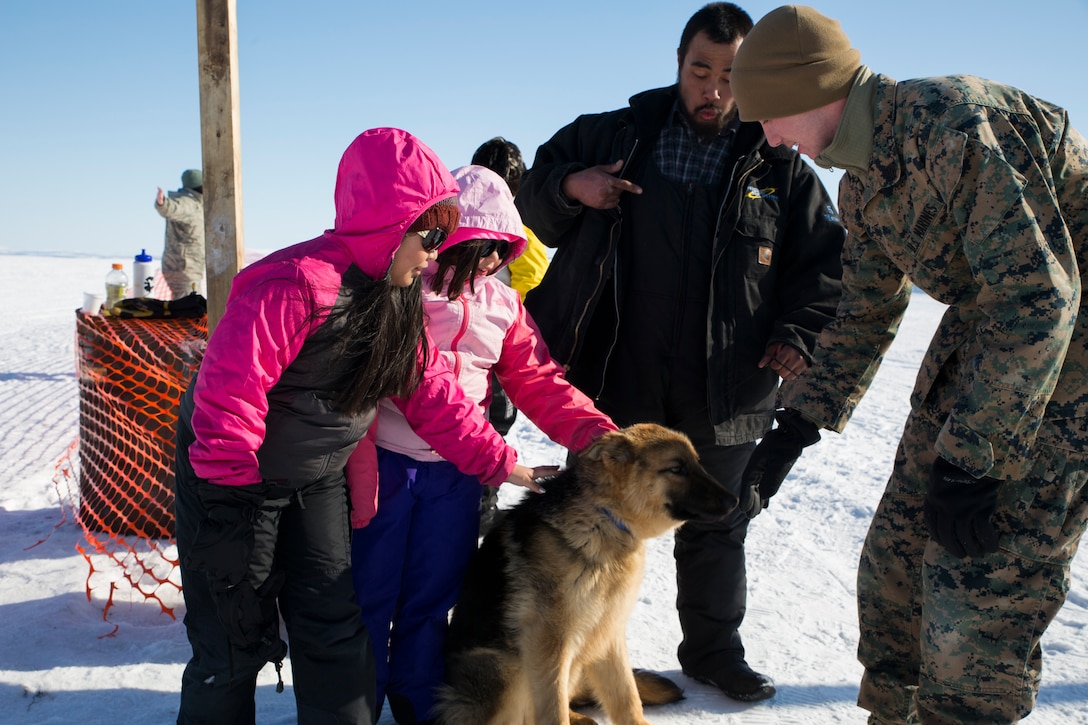 Marine Corps Sgt. Phillip White, right, an embarkation specialist with 4th Marine Logistics Group, interacts with members of the local Kotzebue, Alaska, community, during Innovation Readiness Training Arctic Care 2018, April 15, 2018.