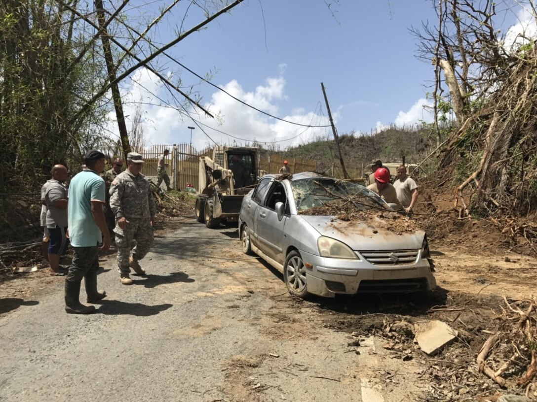South Carolina Army National Guard soldiers work to remove dirt and debris from the driveways for residents of Talante, Puerto Rico.