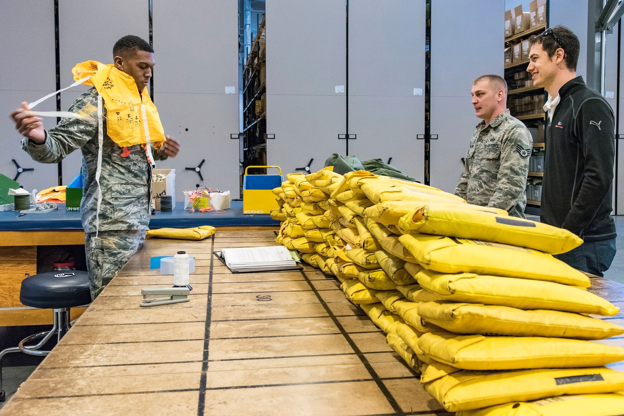 Airman 1st Class Anthony Gray (left), 436th Operations Support Squadron aircrew flight equipment apprentice, demonstrates the inflation procedure for an inflatable life preserver for Joey Logano, driver of the No. 22 Ford in the Monster Energy NASCAR Cup Series April 11, 2018, at Dover Air Force Base, Del. Staff Sgt. Christopher Sharlow (back right), 436th OSS AFE oxygen section NCO in charge, explained the mission of each section within the AFE Flight to Logano during his tour. (U.S. Air Force photo by Roland Balik)