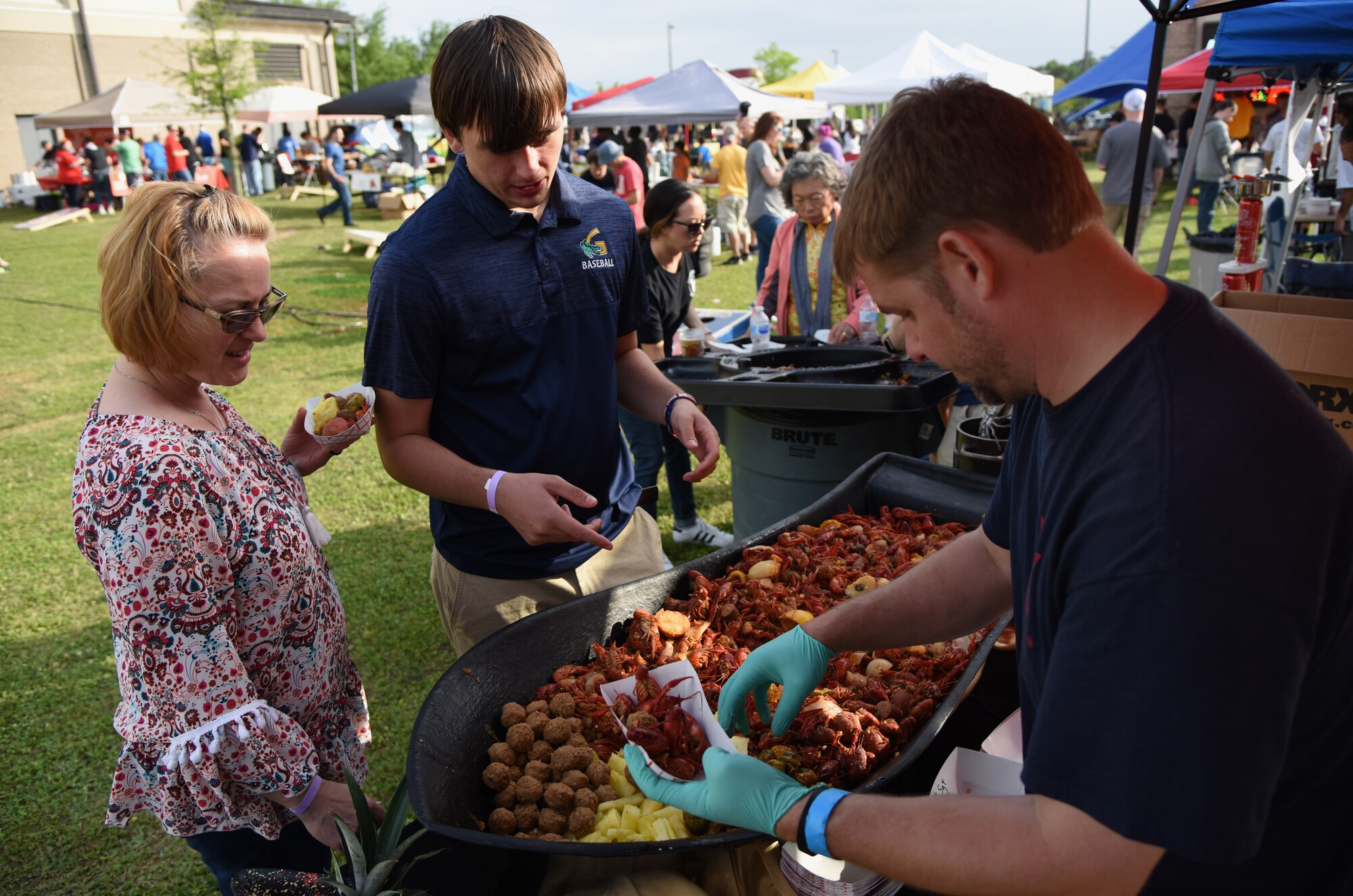 Dustin Polovich, “First Sergeants Council” team member, serves crawfish and ‘fixins’ to Medea Cook, 81st Medical Support Squadron system administrator, and her son, Mathew, during the 6th Annual Bay Breeze Crawfish Cook-Off at the Bay Breeze Event Center at Keesler Air Force Base, Mississippi, April 13, 2018. The “Craw-Fish Pot-Nahs” won first place overall and a free entry into the 26th Annual Mississippi Coast Coliseum Crawfish Festival Cook-Off. (U.S. Air Force photo by Kemberly Groue)