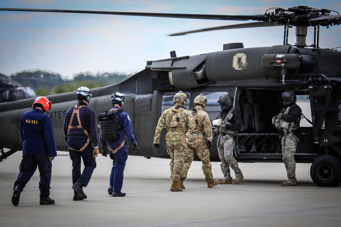 Airmen and civilian board a UH-60L Black Hawk helicopter.