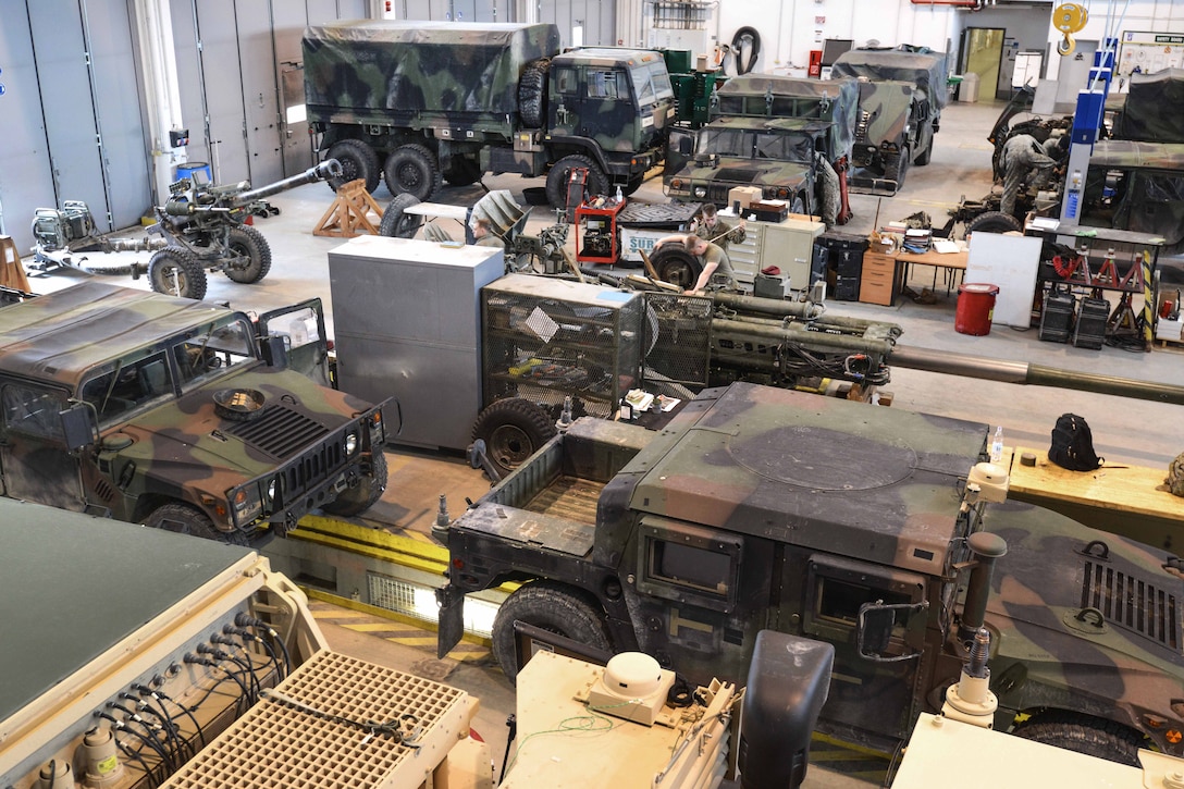 Soldiers perform maintenance on various vehicles and howitzers.