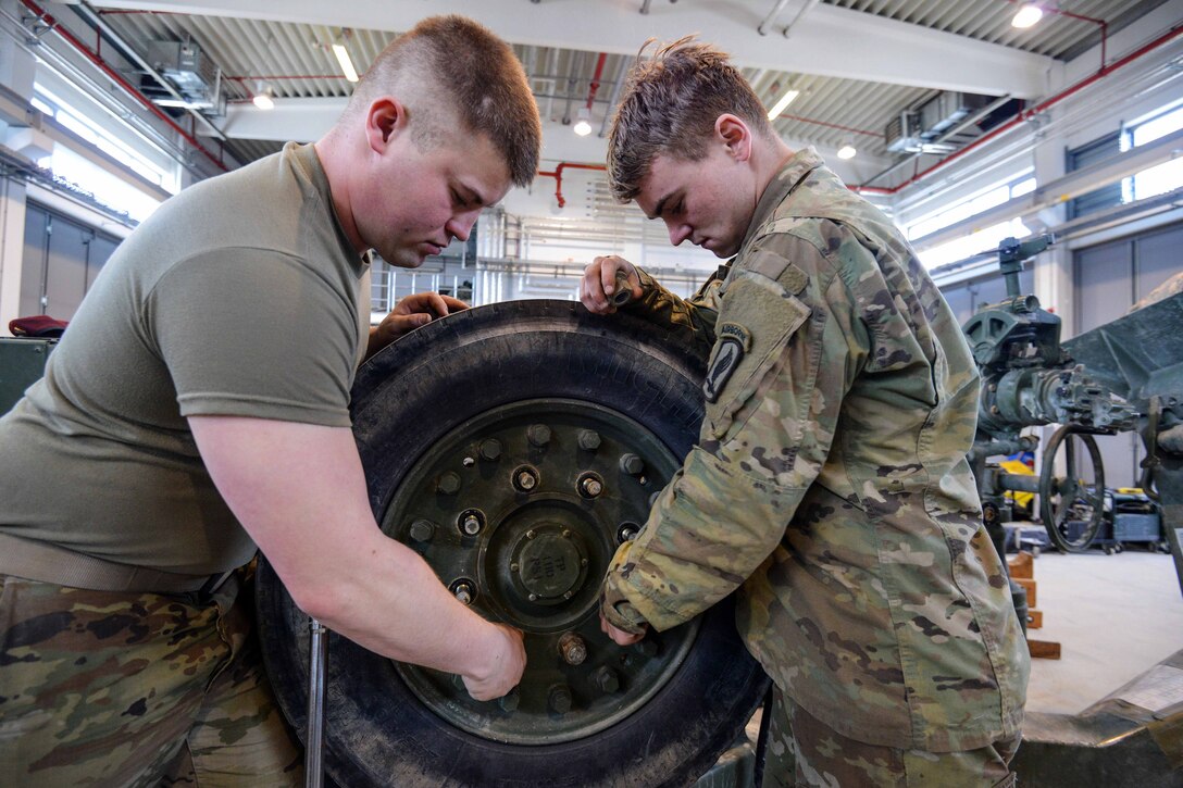 Soldiers replace a wheel on M777 towed 155 mm howitzer.