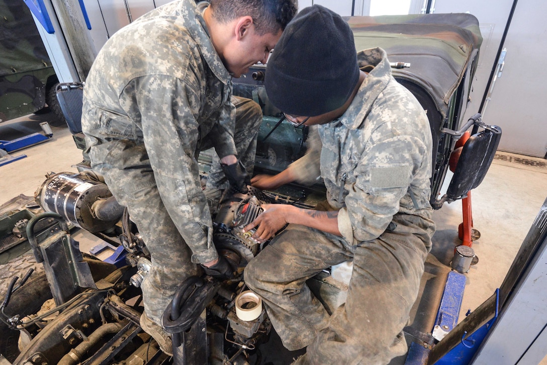 Soldiers perform maintenance on a Humvee vehicle engine.