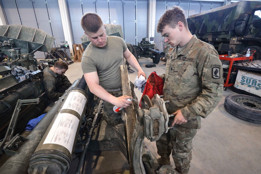 Soldiers perform maintenance on an M777 towed 155 mm howitzer.