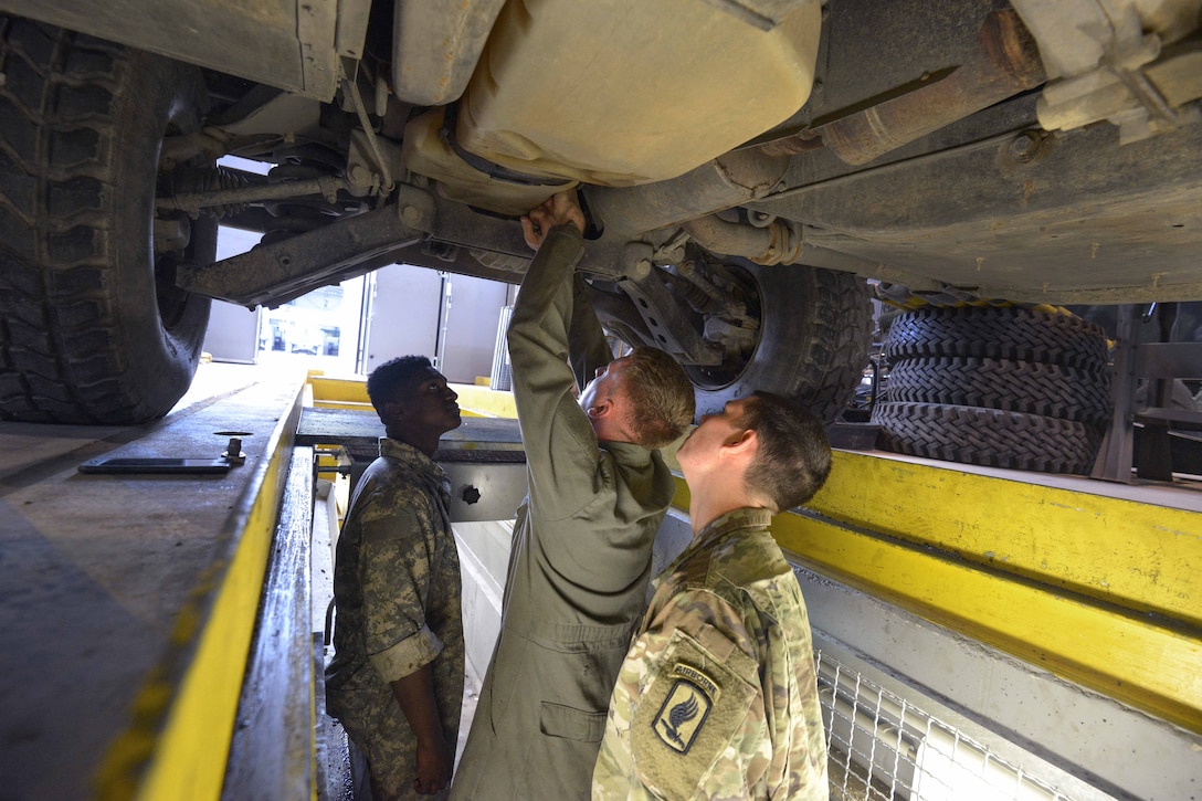 Soldiers perform maintenance on a Humvee vehicle engine.