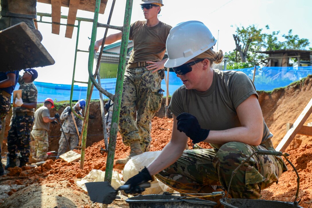 A sailor uses stucco to complete the construction project.