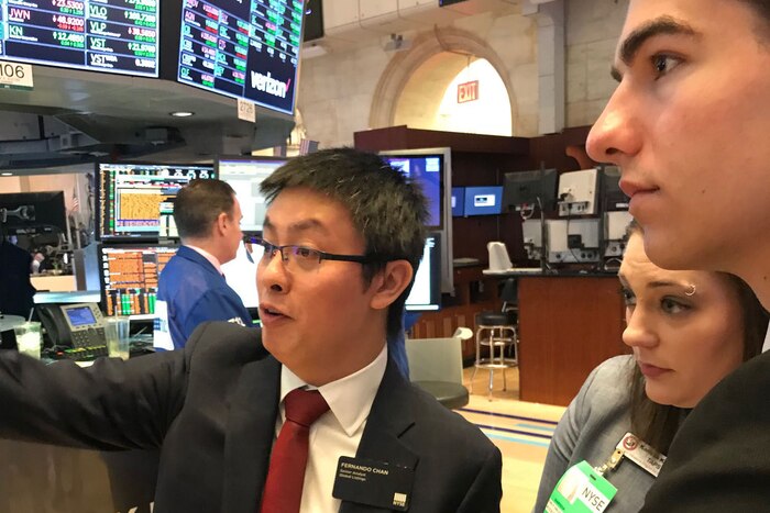 A man gives a tour for two children at the New York Stock Exchange.