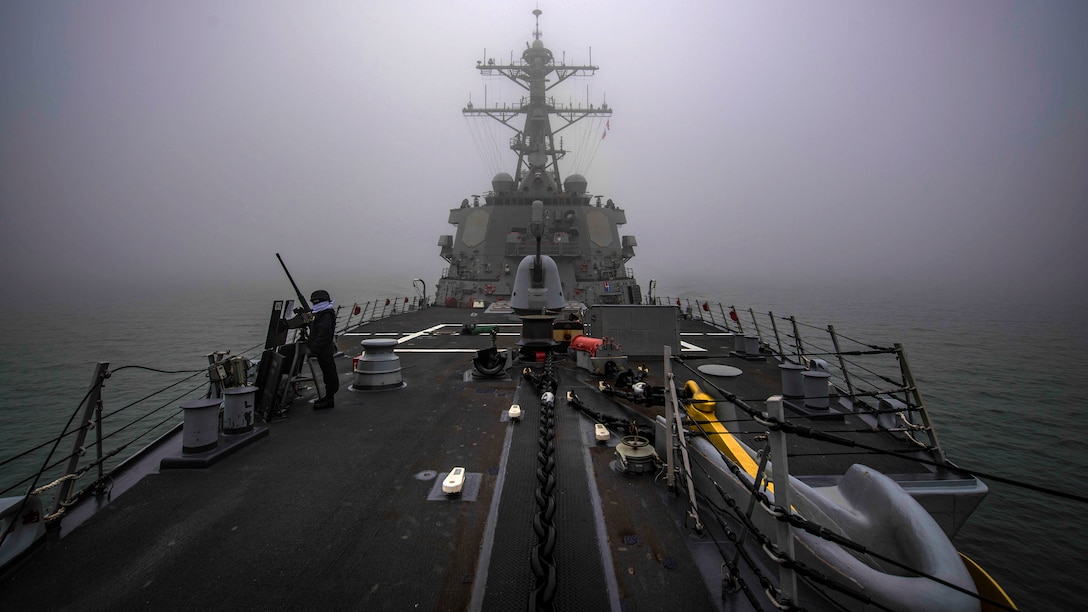 A ship sails through the water with fog.