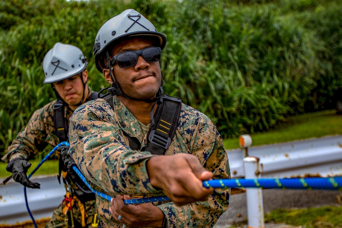 Two Marines pull a rope.