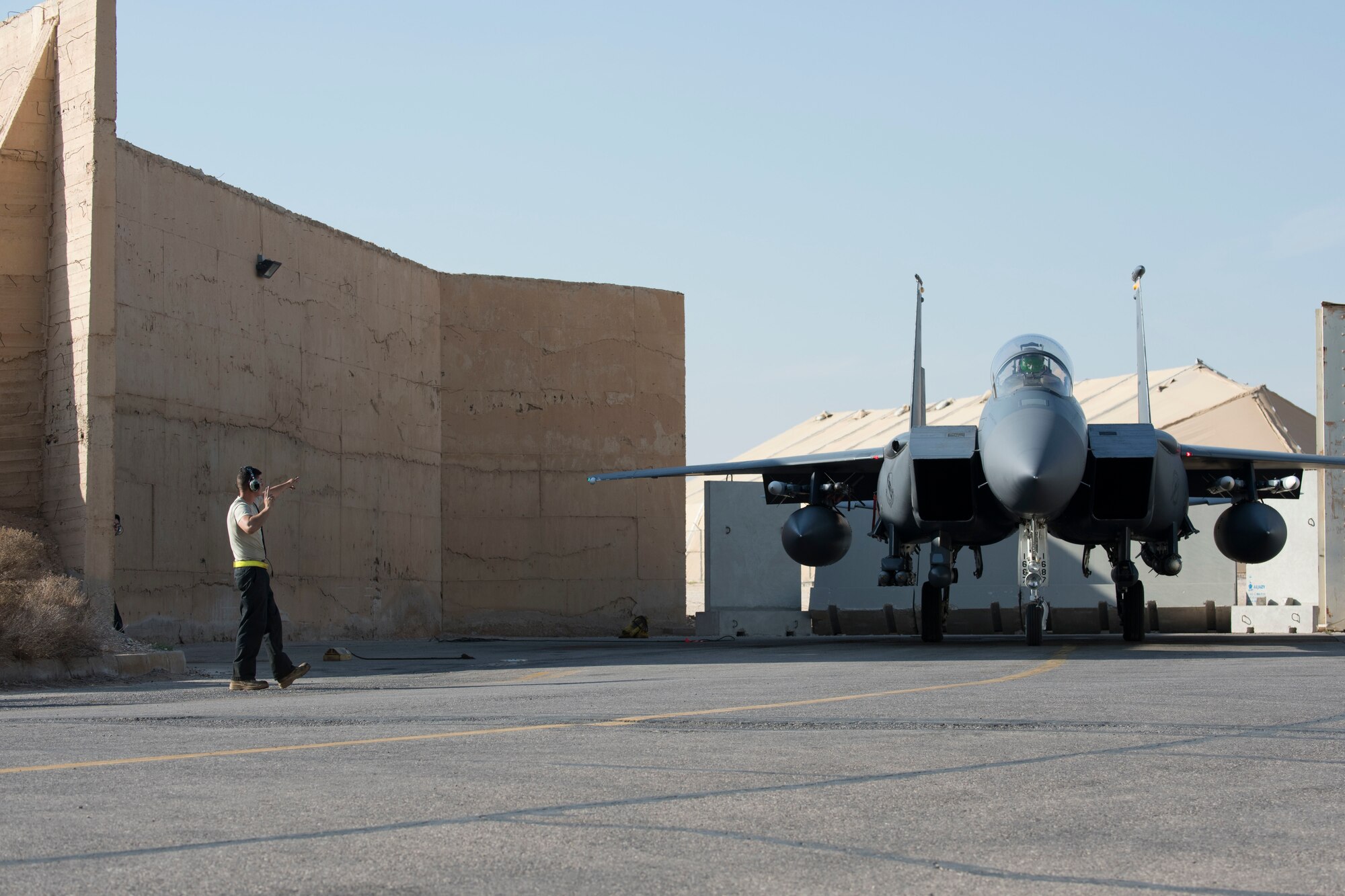 A 332nd Expeditionary Maintenance Squadron crew chief directs an F-15E Strike Eagle out of its hanger before takeoff March 7, 2018, at an undisclosed location in Southeast Asia.