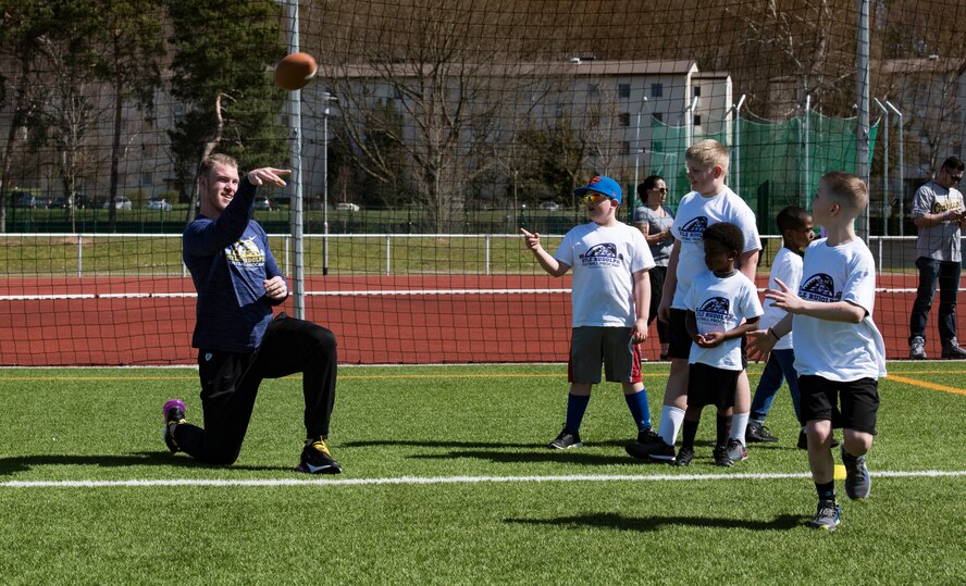 Kyle Rudolph, NFL Minnesota Vikings tight end, helps camp attendees with their catching skills during a free NFL football camp at the Kaiserslautern High School football stadium April 7, 2018 on Kapaun Air Base, Germany. Rudolph taught camp attendees how to catch and carry the football during the two-day camp.