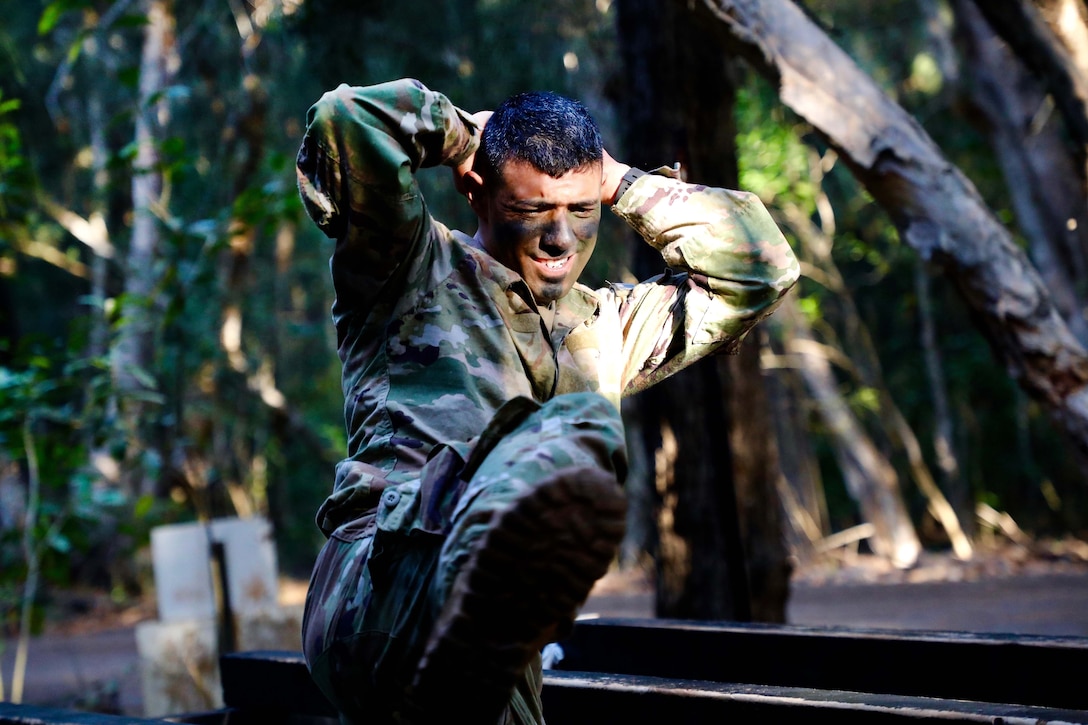 A soldier high steps over an obstacle.