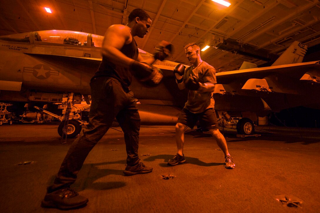 Two marines box next to aircraft and equipment.