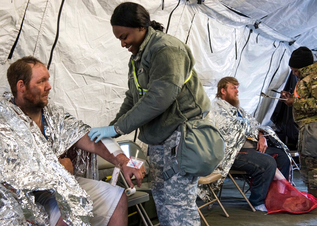 Soldiers record vital signs and document injuries of civilian mock casualties.