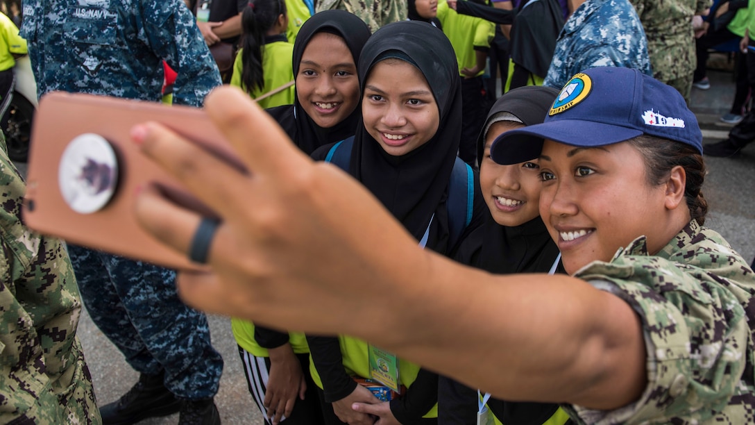 A sailor holds a phone to take a group photo.