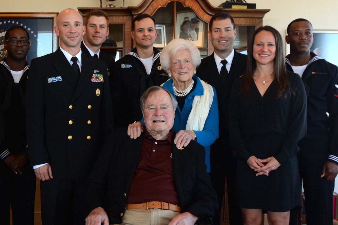 Sailors and civilians stand around former President George H.W. Bush and his wife Barbara Bush.