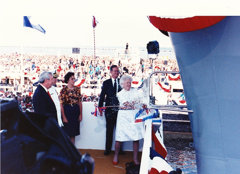 Ship sponsor first lady Barbara Bush breaks a bottle of champagne on the bow of the aircraft carrier USS George Washington as President George H.W. Bush looks on in Newport News, Va., July 21, 1990.