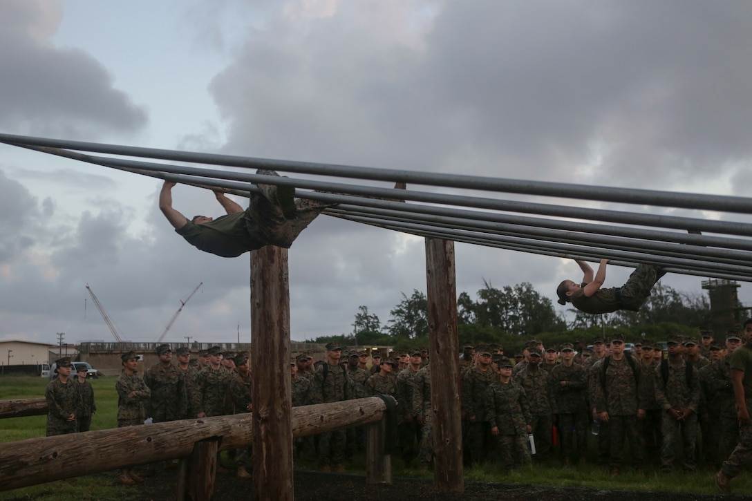 U.S. Marine Corps 1st Lt. Seth R. Hole, left, and Capt. Melissa S. Mocello demonstrate how to maneuver through the parallel bars of an obstacle course to a group of Marines with U.S. Marine Corps Forces, Pacific (MARFORPAC) at Landing Zone Boondocker on Marine Corps Base Hawaii April 13, 2018. Hole is a comptroller and Mocello is a supply officer both with Headquarters and Service Battalion, MARFORPAC. The Marines completed the obstacle course and leader’s reaction course to improve combat conditioning and enhance small unit leadership skills. (U.S. Marine Corps photo by Lance Cpl. Adam Montera)