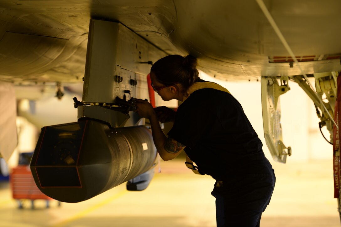 An airman examines part of an aircraft.
