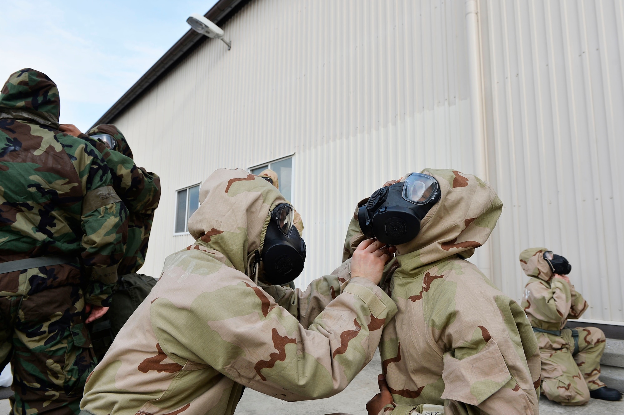 U.S. Airmen assigned to the 86th Civil Engineer Group on Ramstein Air Base, Germany, assist each other in donning protective gear during an exercise training service members to respond to chemical, biological, radiological, and nuclear threats, April 12, 2018. The Air Force requires service members to maintain ample knowledge of CBRN operations regardless of rank or career field. (U.S. Air Force photo by Senior Airman Joshua Magbanua)