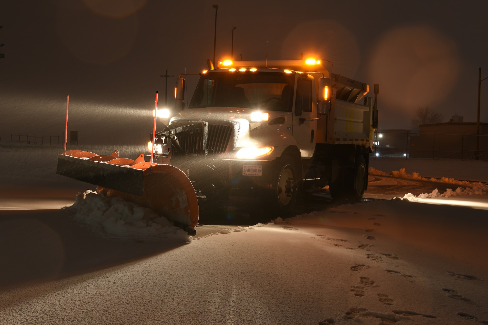 A 28th Civil Engineer Squadron chip truck clears snow in a parking lot during a snowstorm at Ellsworth Air Force Base, S.D., April 13, 2018. Non-essential base functions were suspended due to inclement weather, but heavy equipment operators continued on staggered shifts to remove snow and improve driving conditions. (U.S. Air Force photo by Airman 1st Class Thomas Karol)