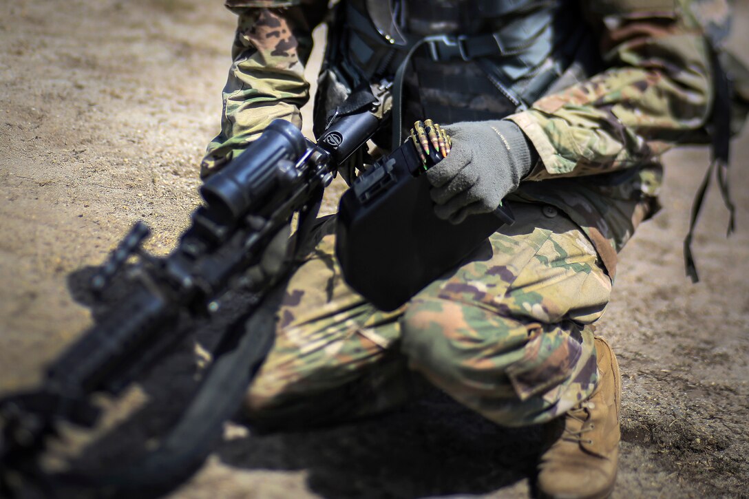 A soldier loads his weapon with ammunition.