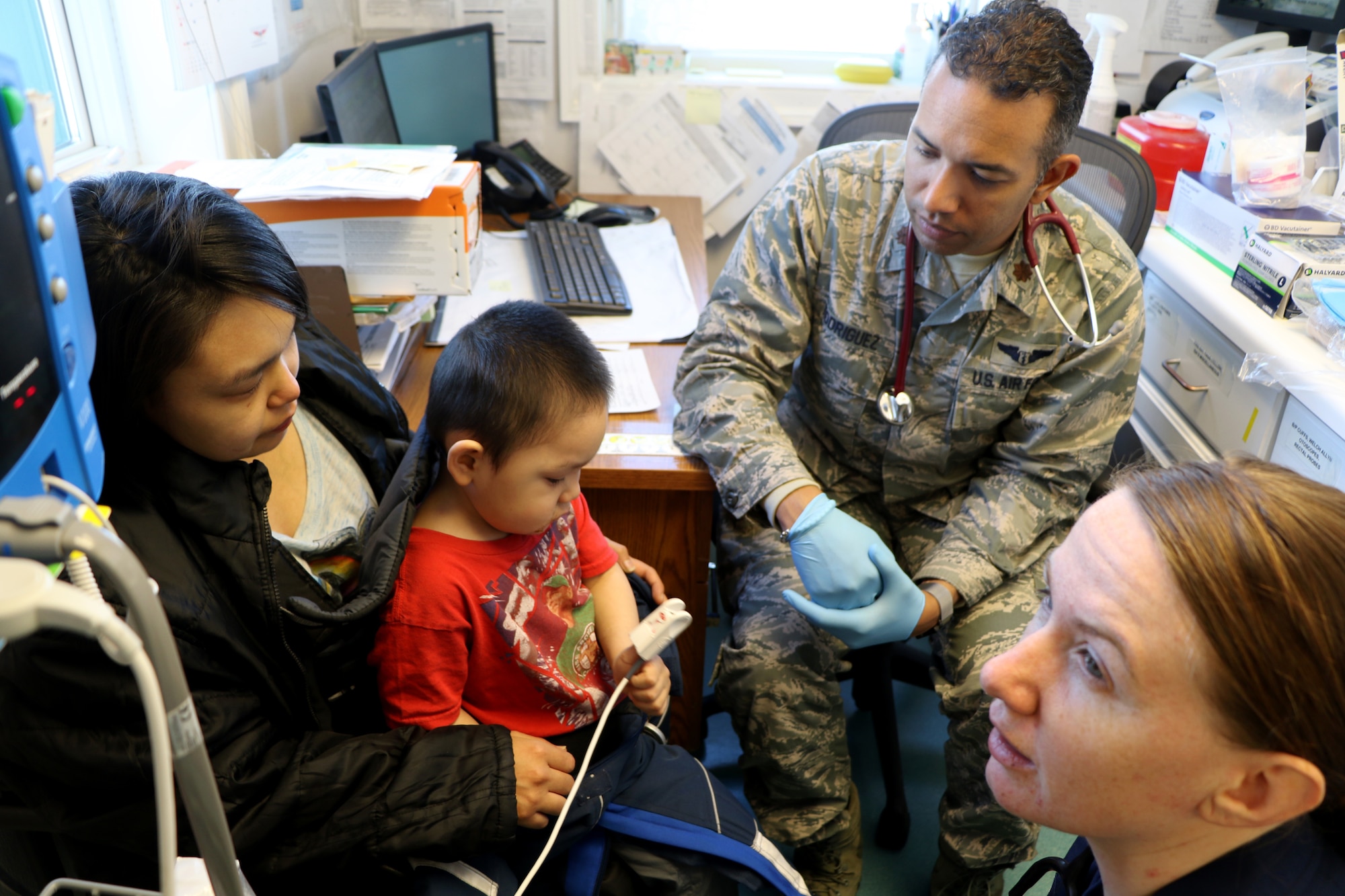 United States Coast Guard Heath Service Technician Third Class Annice Hand (front), checks the amount of oxygen in the blood of a young patient alongside Major Vashun Rodriguez a flight surgeon assigned to the 927th Aeromedical Staging Squadron, MacDill Air Force Base FL, at the Kivalina Clinic, Kivalina, Alaska, April 17, 2018. Military personnel supporting Arctic Care 2018 accomplished critical mission training while providing medical, dental, optometry and veterinary care for underserved villages in the Maniillaq Service Area April 16-24. (U.S. Air Force photo by Maj. Joe Simms)