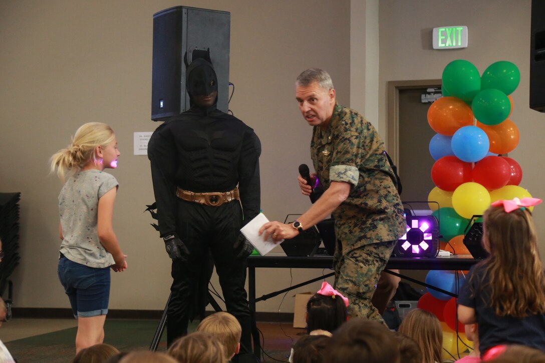 Lt. Cmdr. Greg Uvila, regimental chaplain, 7th Marine Regiment, and Batman welcome a child up to the stage at the Child Abuse Awareness and Military Child Appreciation Carnival aboard the Marine Corps Air Ground Combat Center, Twentynine Palms, Calif., April 12, 2018. The event was held to provide available resources to community members and hold a small fair for children. (U.S. Marine Corps photo by Lance Cpl. Preston L. Morris)