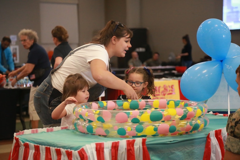 A mother helps her children play a carnival game at the Child Abuse Awareness and Military Child Appreciation Carnival aboard the Marine Corps Air Ground Combat Center, Twentynine Palms, Calif., April 12, 2018. The event was held to provide available resources to community members and hold a small fair for children. (U.S. Marine Corps photo by Lance Cpl. Preston L. Morris)