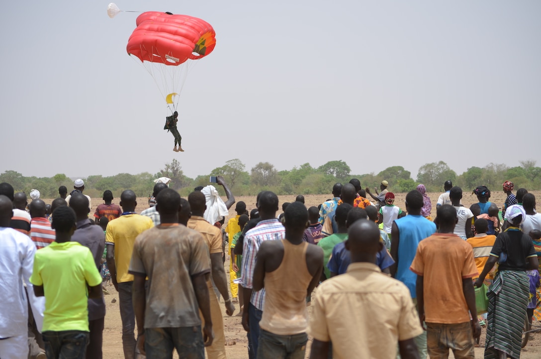 A member of the Burkinabe free fall team lands in front of local villagers.