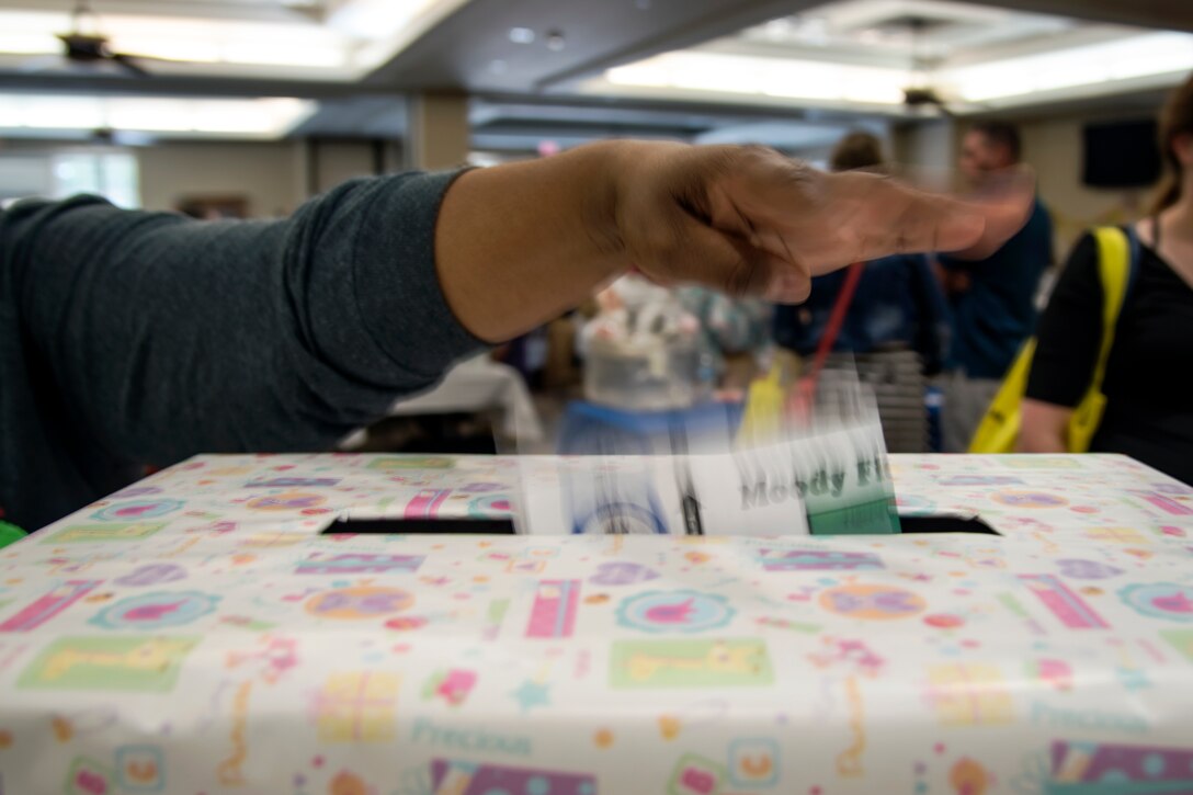 Lawonna Barron, 23d Medical Operations Squadron Family Advocacy Program anger management counselor, drops a sign-off sheet into a raffle box, April 14, 2018, at Moody Air Force Base, Ga.  The baby shower provided attendants with various gifts and educational opportunities, the shower’s main focus this year was on raising awareness to the issue of child abuse. (U.S. Air Force photo by Airman 1st Class Eugene Oliver)