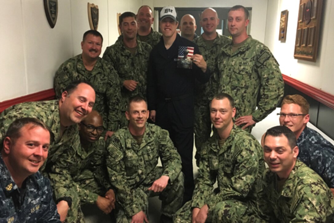 Sailors pose for a photo with a NASCAR driver.