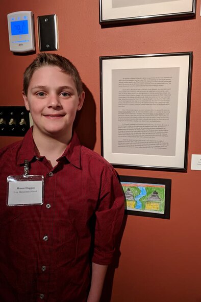 Mason Duggan, son of Lt. Col. Jerrod Duggan, 341st Maintenance Group deputy commander, poses next to his essay displayed at a museum March 2, 2018, in Great Falls, Mont.