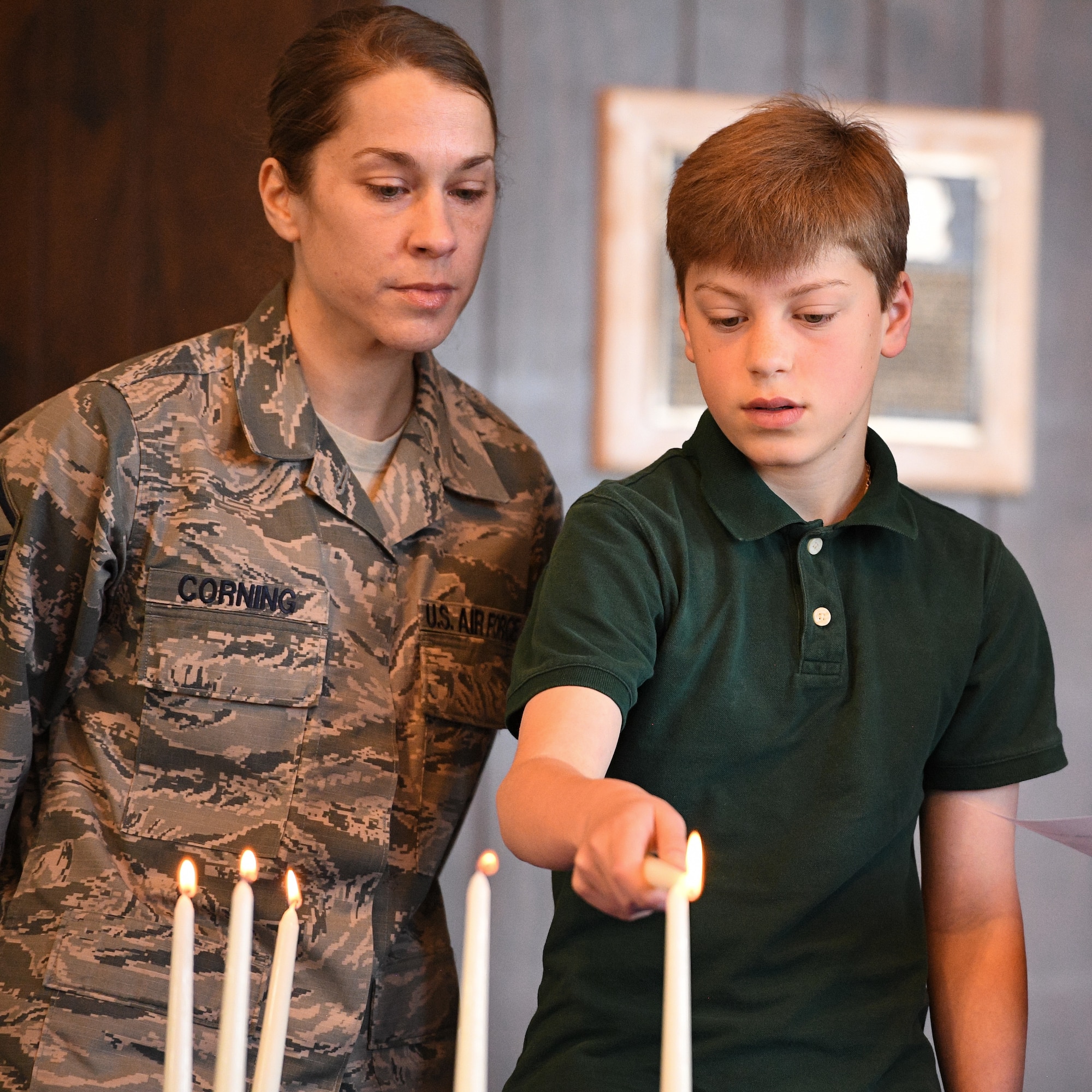 Evan Corning lights candles alongside his mother, Master Sgt. Michele Corning, during the Holocaust Days of Remembrance Service April 18, 2018, at Hill Air Force Base, Utah. The event's guest speaker was Diane Warsoff, a resident of Utah and second-generation Holocaust survivor. (U.S. Air Force photo by R. Nial Bradshaw)