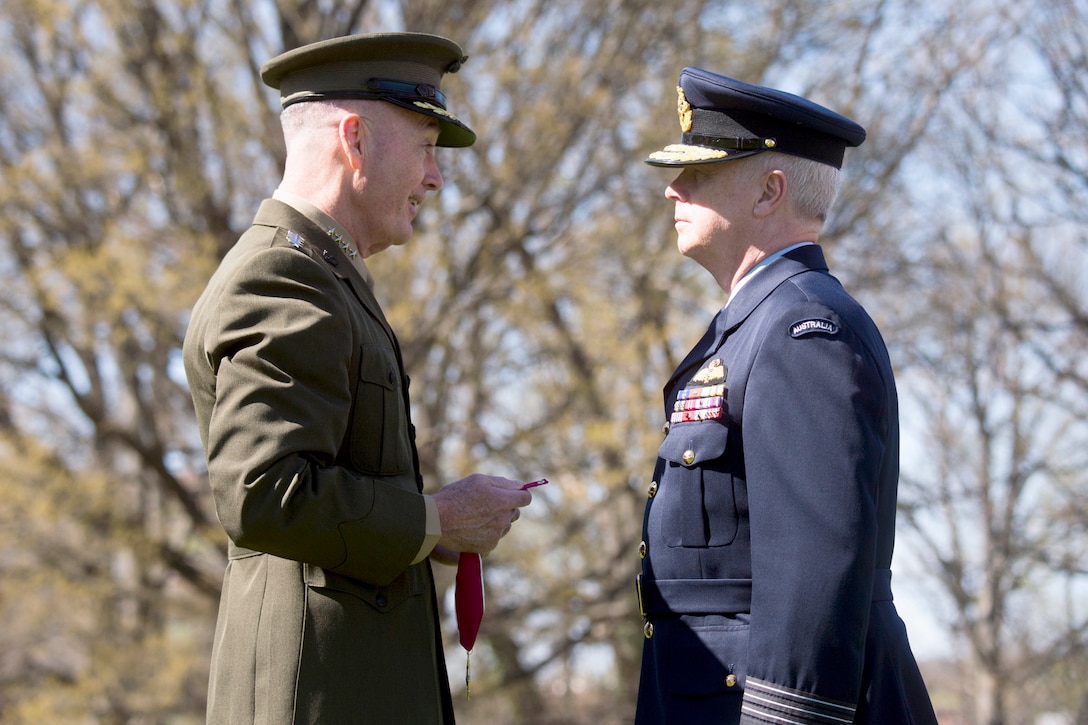 The chairman of the Joint Chiefs of Staff holds the Legion of Merit while standing in front of the chief of the Australian defense force.