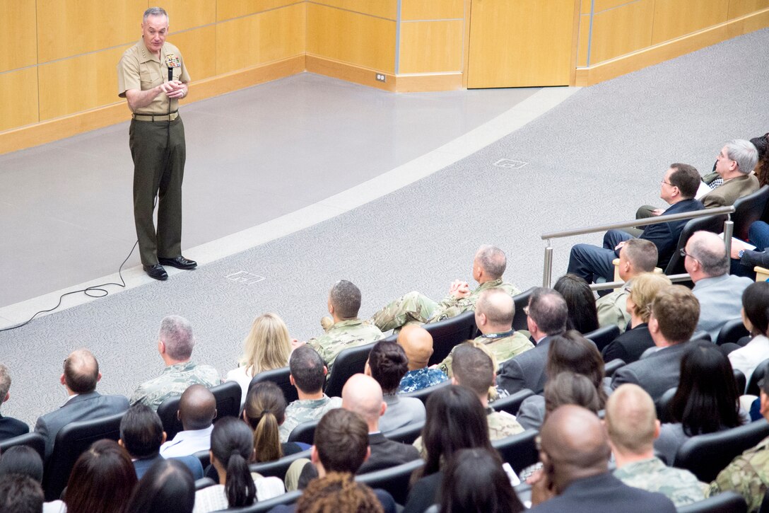 The chairman of the joint chiefs of staff stands on stage in front of an audience.