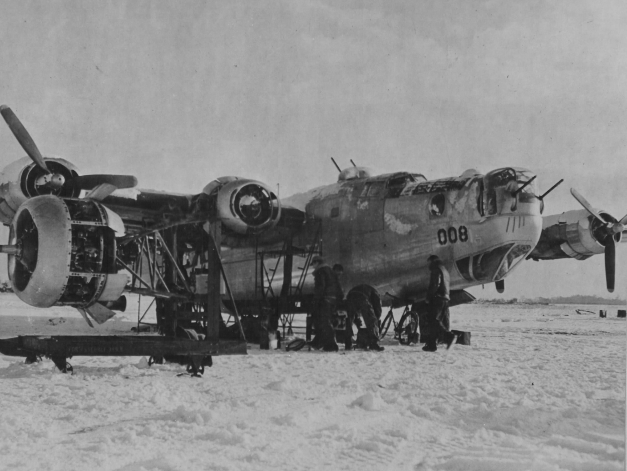 Ground crew changing an engine on a B-24 in the snow at an Eighth Air Force base in England.  Most maintenance was done outdoors regardless of the season or weather.
