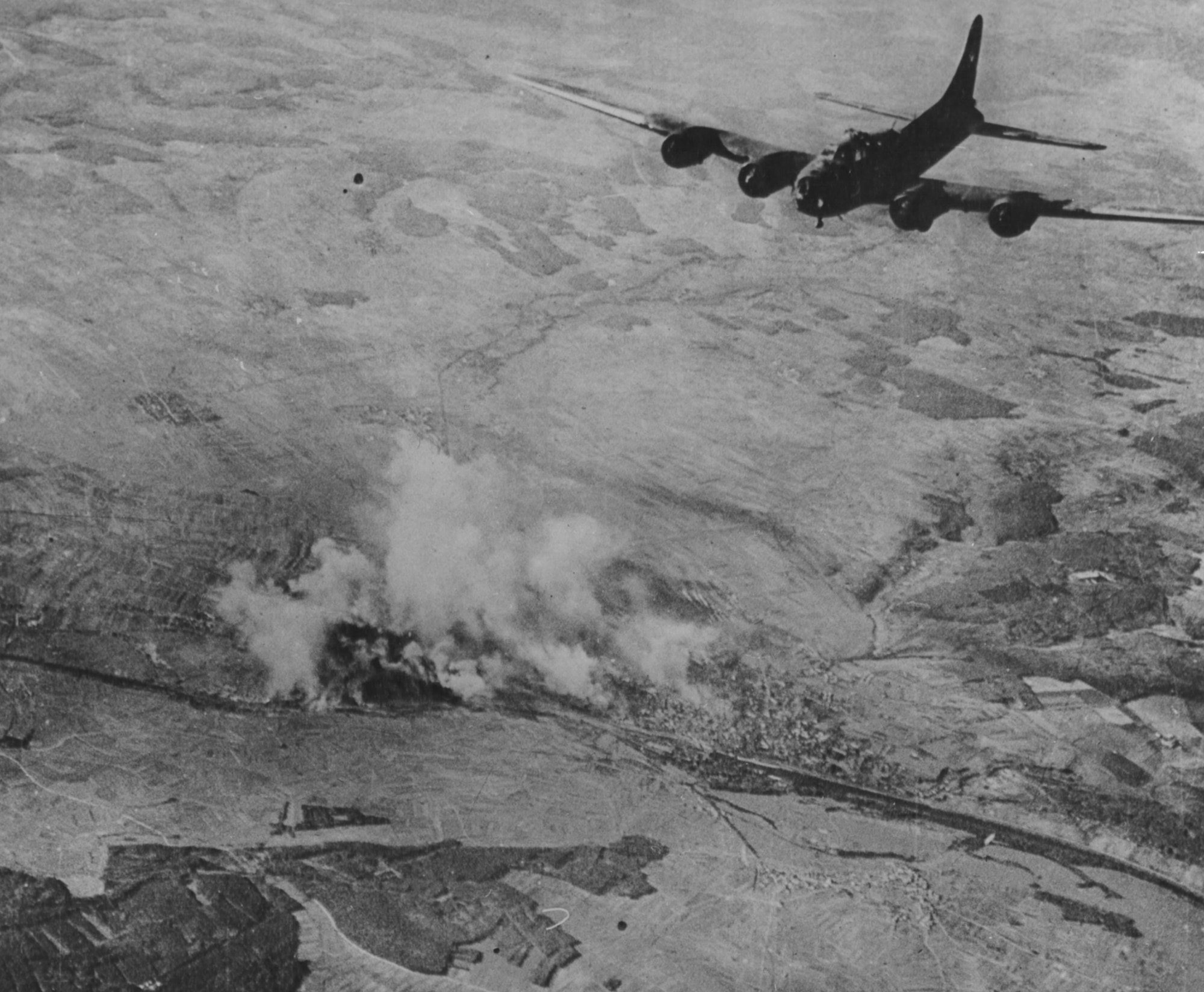 Schweinfurt in flames while a B-17 heads for home Black Thursday after bombing.