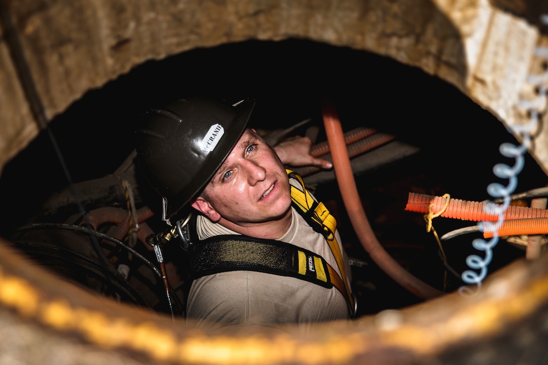 An airman looks up though a manhole.