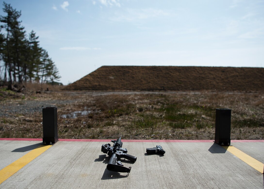 An M4 carbine and an M9 pistol sit on the ground of the new 35th Security Forces Squadron Combat Arms Training and Maintenance outdoor firing range at Draughon Range adjacent Misawa City, Japan, April 18, 2018. Conceptualized nearly three years ago, the outdoor range provides CATM six times more space to qualify Airmen on a variety of weapons. The current indoor range can qualify seven Airmen at one time, where the outdoor range serves 40. (U.S. Air Force photo by Staff Sgt. Deana Heitzman)