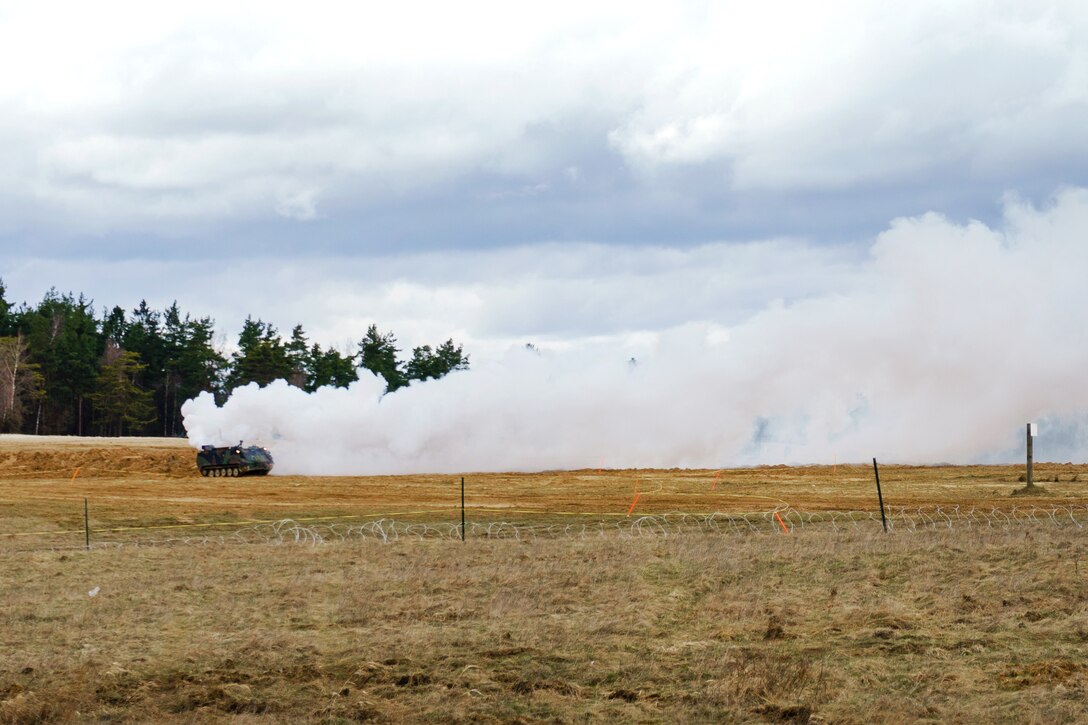 An M58 Wolf unmanned vehicle lays smoke for concealment.