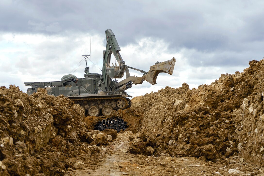 British soldiers operate a Terrier armored digger remotely.
