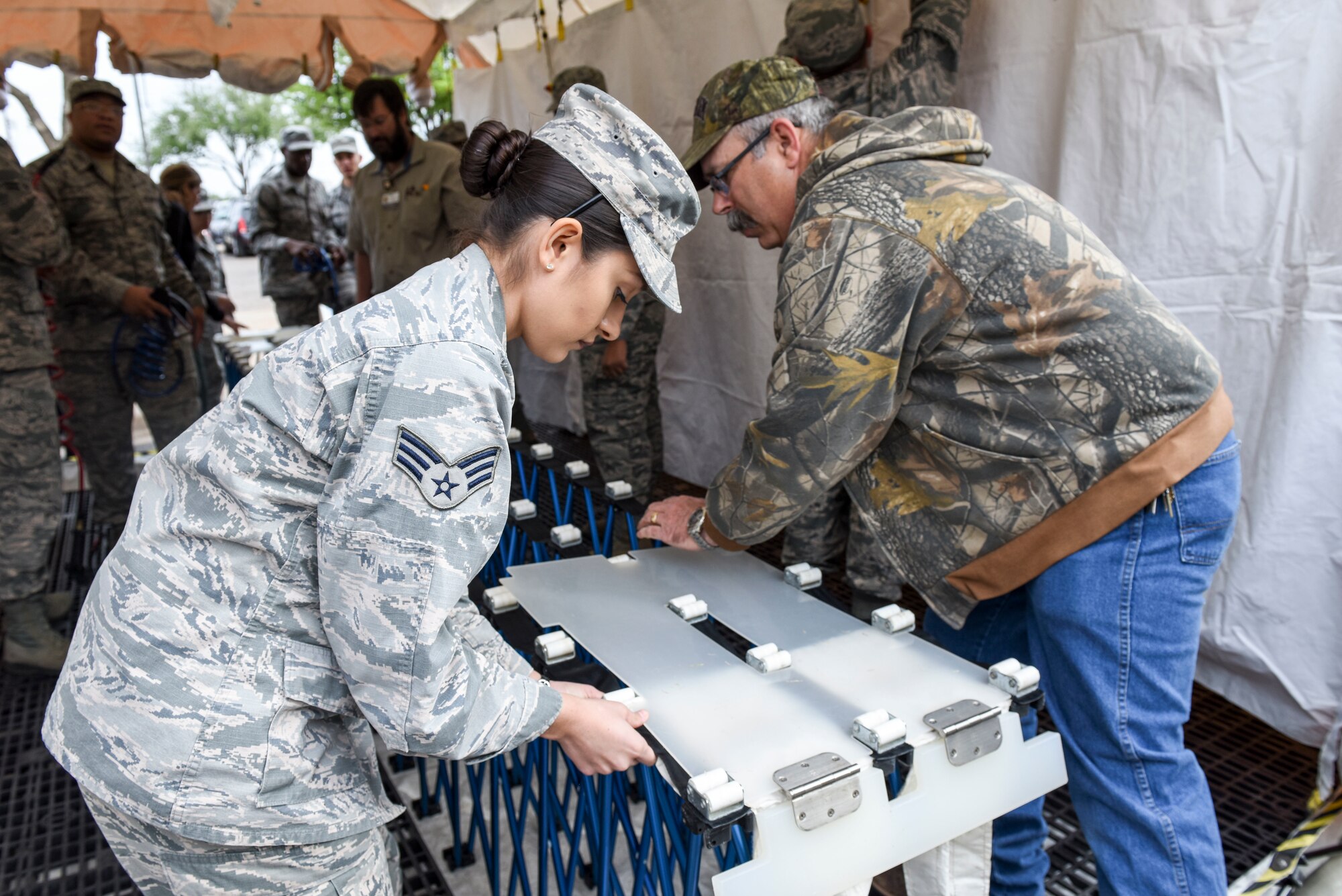 U.S. Air Force Senior Airman Anallely Mendoza Cuevos, 17th Medical Group lab technician, works with San Angelo Community Medical Center nurse, Todd Castlebury, to assemble the patient litter conveyor at the San Angelo Community Medical Center, San Angelo, Texas, April 19, 2018. The patient litter conveyor allows individuals who cannot walk to be transported through the decontamination tent using this conveyor in the event of an emergency.  (U.S. Air Force photo by Aryn Lockhart/Released)
