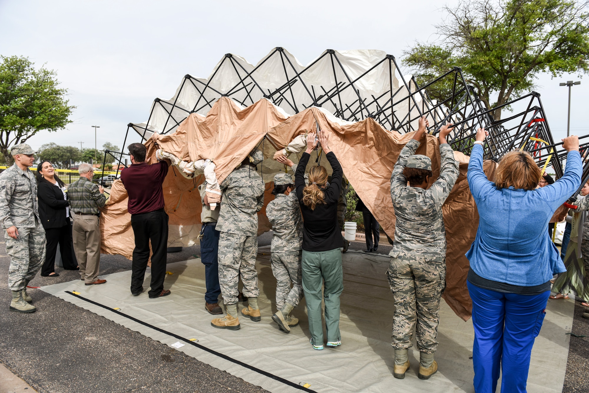 17th Training Wing Medical Group members work with San Angelo Community Medical Center employees to assemble a decontamination tent during a training exercise at San Angelo Community Medical Center, San Angelo, Texas, April 19, 2018. SACMC and Goodfellow organized the training opportunity as a part of  a current community partnership agreements.  (U.S. Air Force photo by Aryn Lockhart/Released)