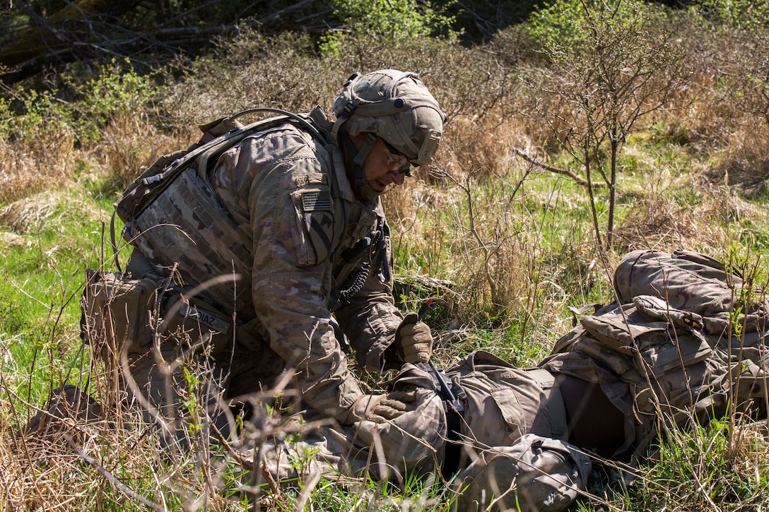 A soldier applies a tourniquet on another soldier.