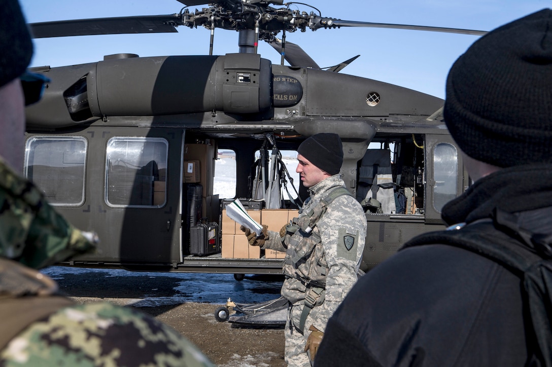 Service members receive a safety brief before boarding a helicopter.