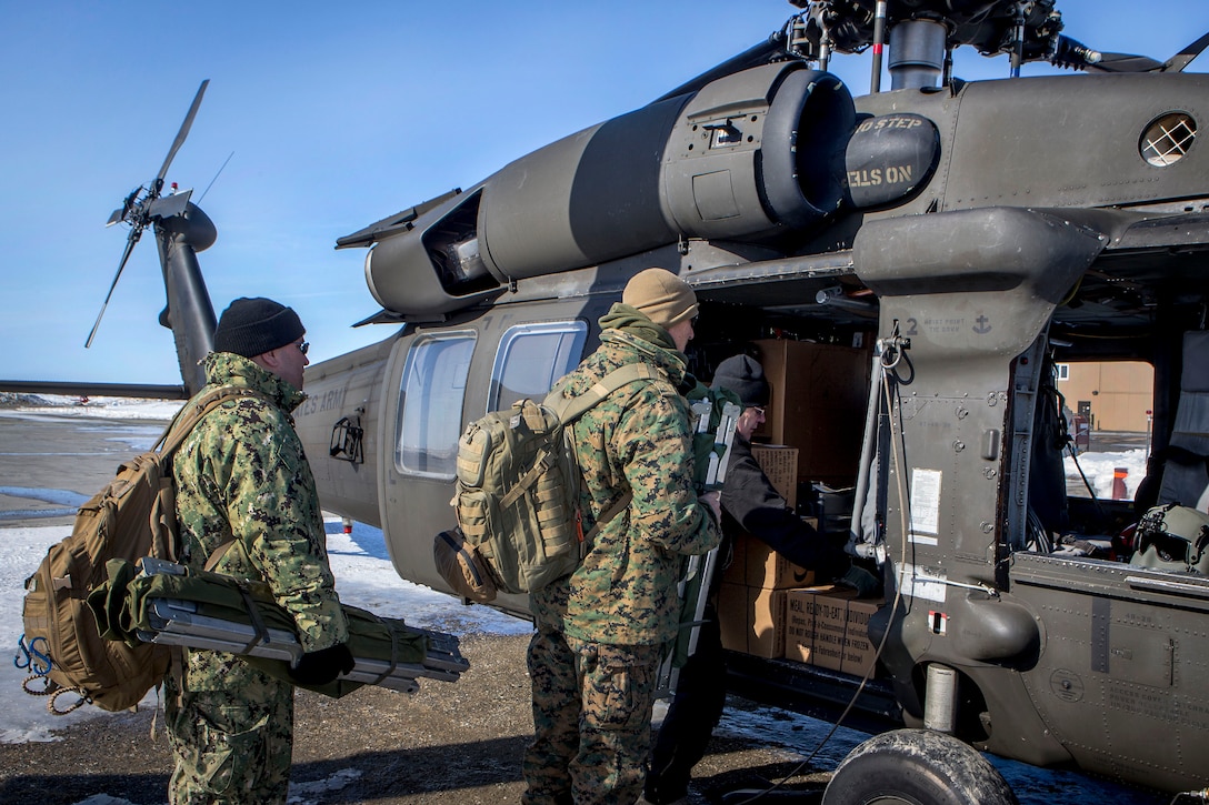 Sailors load their gear and supplies into a helicopter.