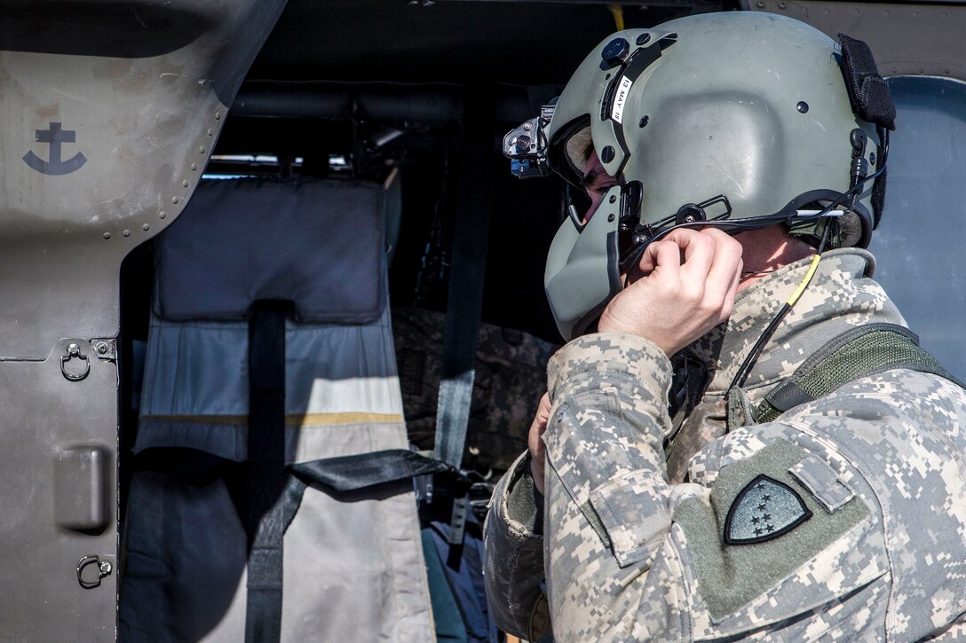 An Army crew chief adjusts his gear.