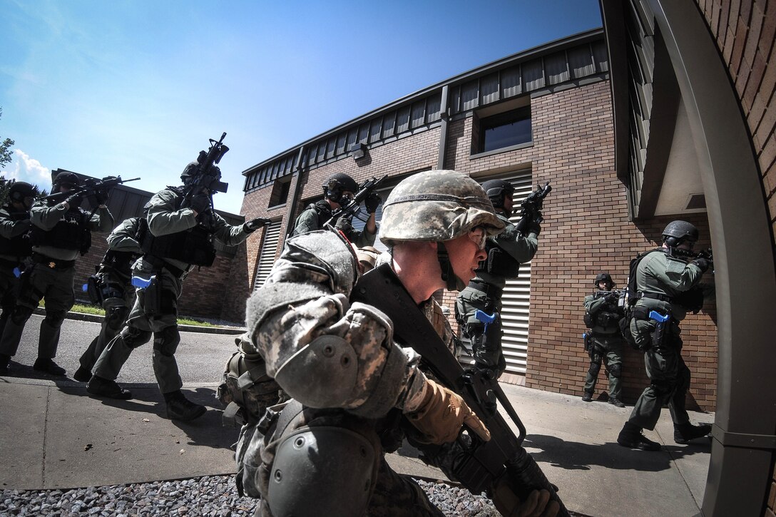 Cadets provide security for civilian police entering a building.